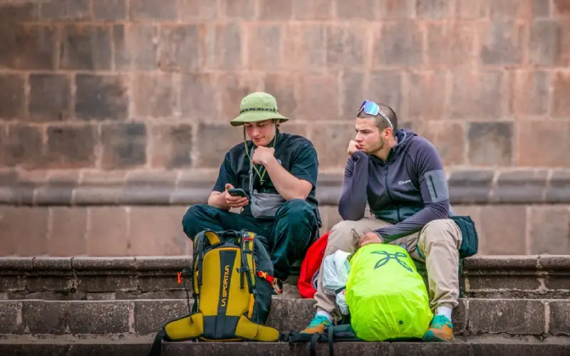 turistas esperando sentados en una plaza