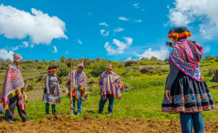 Travelers sharing a cultural experience with the Amaru community near Cusco, Peru, with traditional clothing, open fields, and Andean mountains nearby.