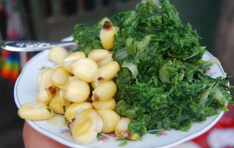 Plate of yuyo haucha, sautéed Andean wild greens, served with boiled mote corn on the side.