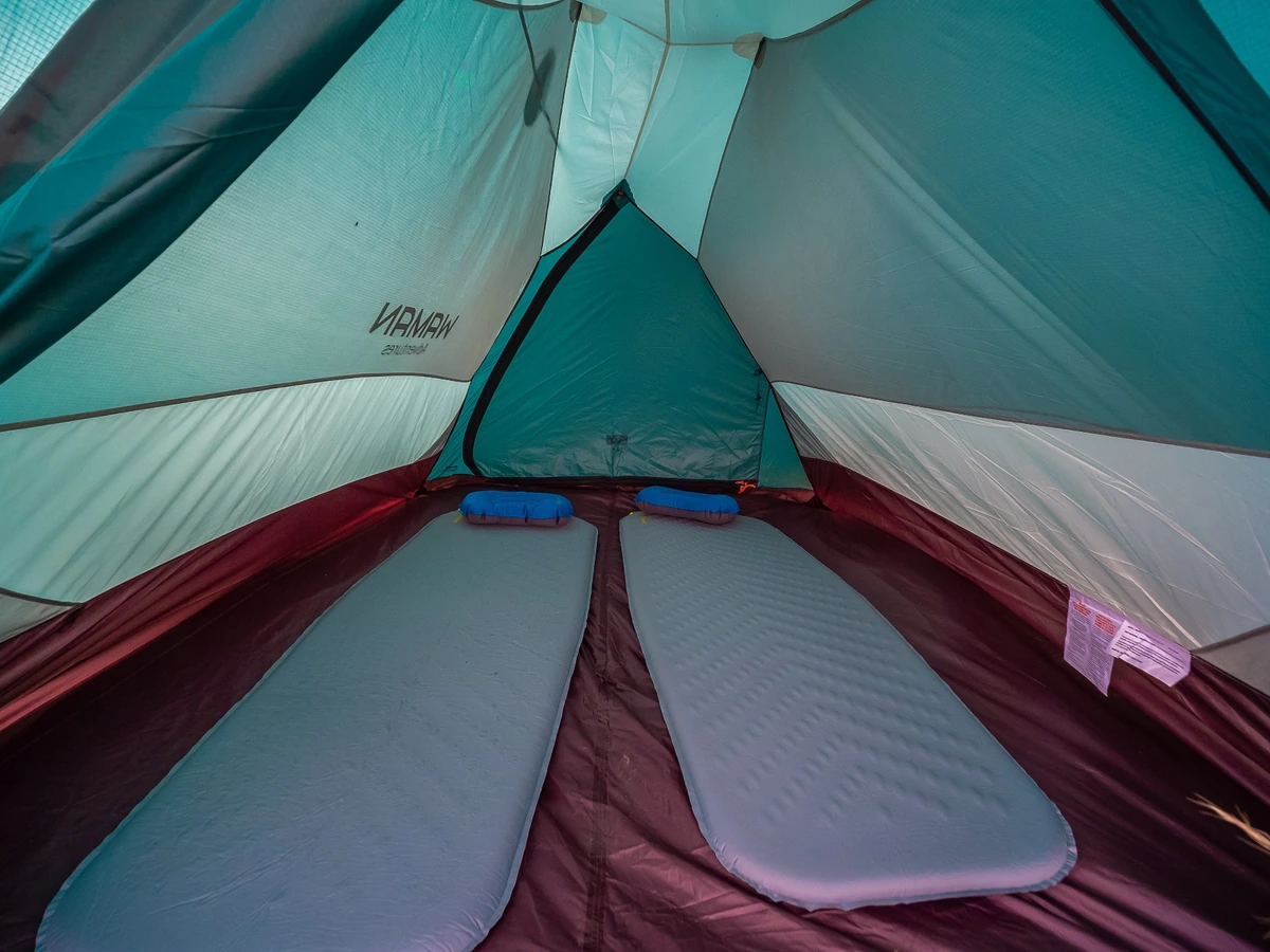 Dos colchones inflables con almohadas azules preparados dentro de una tienda para acampar en el Camino Inca.